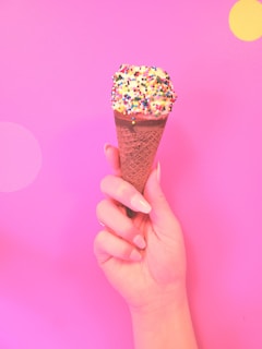 A cheerful child holding a cone filled with colorful sprinkles.