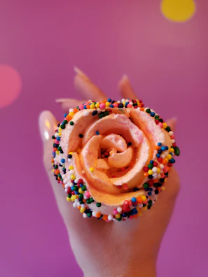 Close-up of a hand coloring a cheerful kawaii cupcake with bright markers.