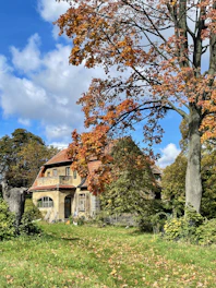 Cozy rural house surrounded by trees and natural landscape under a clear sky.