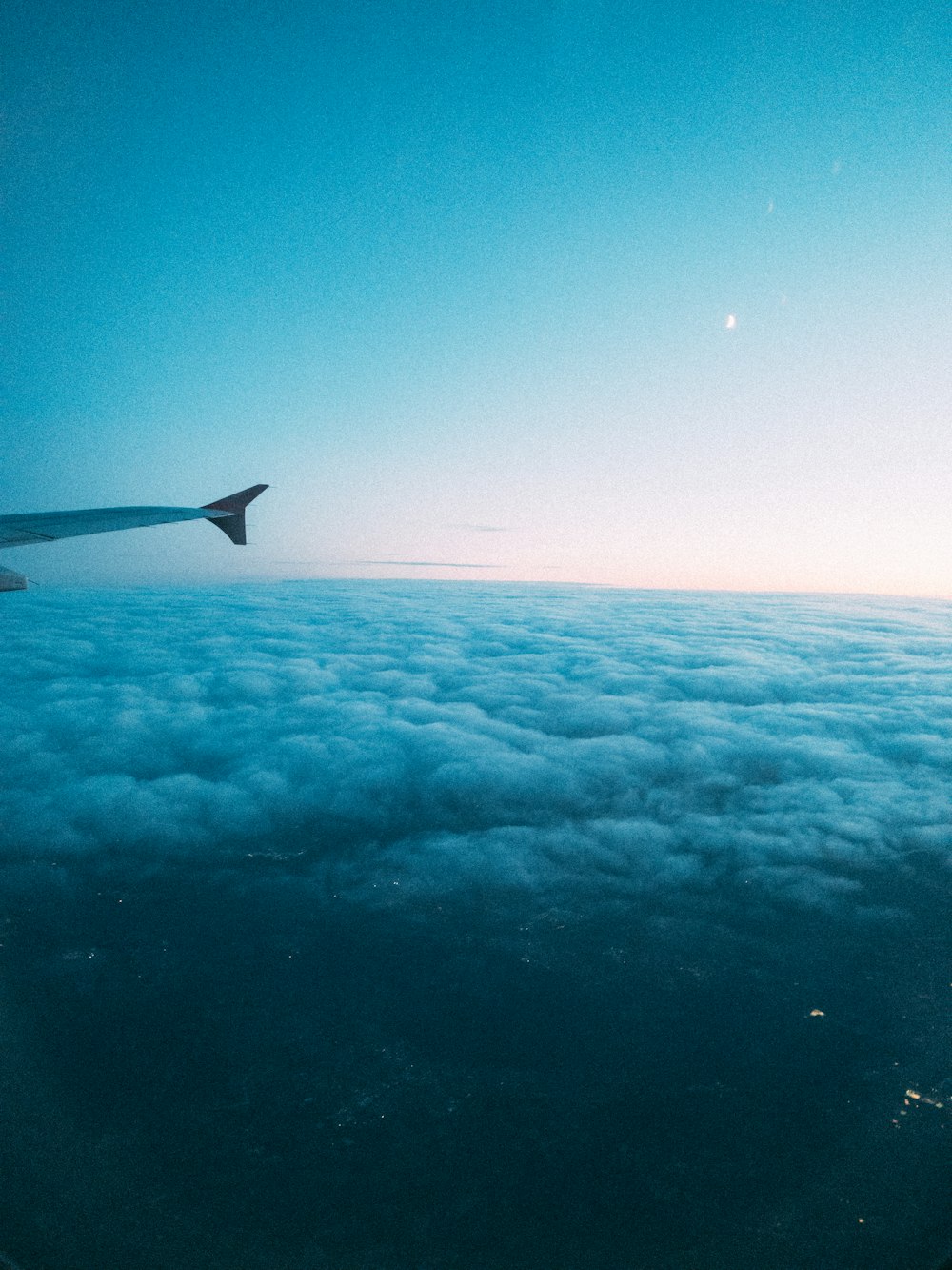 a view of the wing of an airplane above the clouds