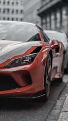 Close-up shot of a sleek red sports car reflecting sunlight on a city street.