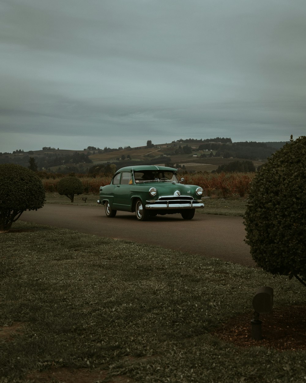 a green car is parked on the side of the road