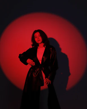 A dramatic black background with a subtle red light highlighting a sleek leather harness.