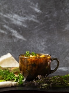A rustic kitchen table with fresh herbs, colorful vegetables, and a steaming bowl of healing soup.