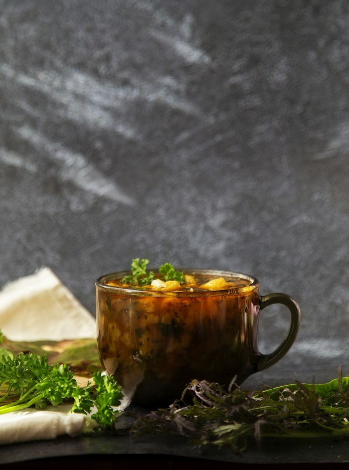 Rich dark beef bone broth in a mug with herbs