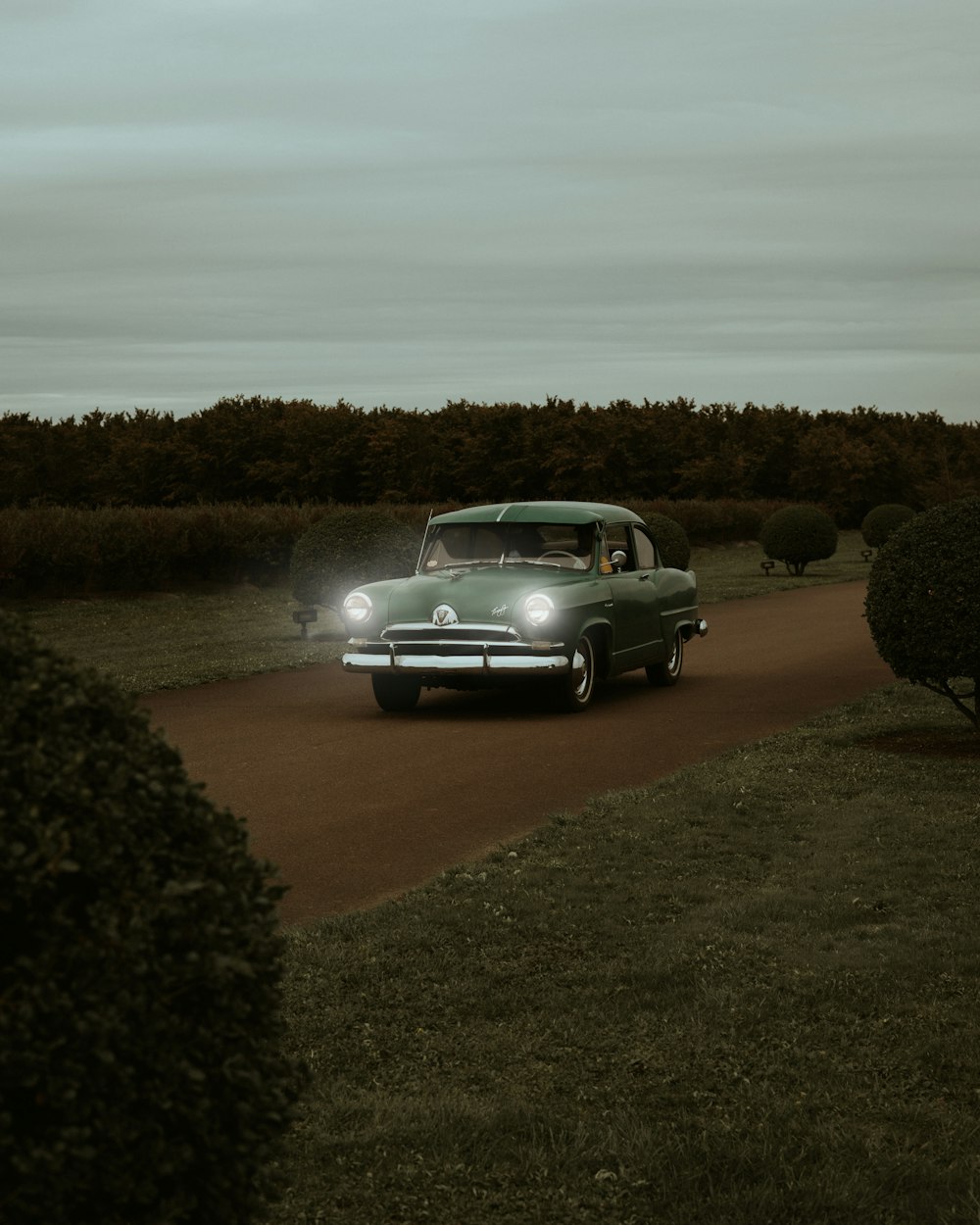 a green car driving down a dirt road