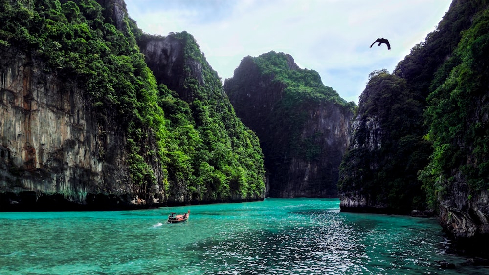 a person in a boat in a body of water surrounded by mountains