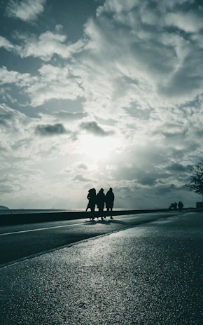 Silhouetted men walking together along a stormy coastline, embodying brotherhood and perseverance.