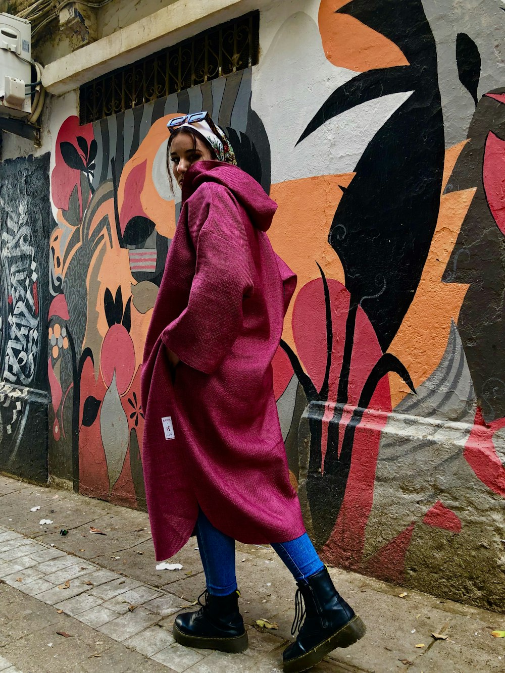 a woman in a pink coat walking down the street