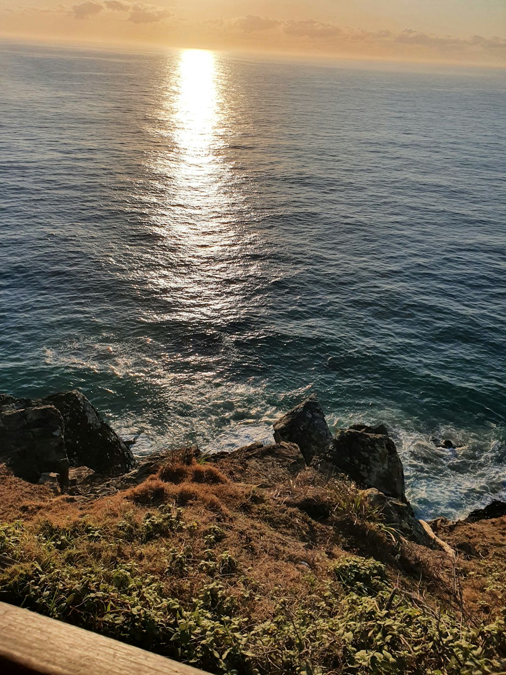 a bench sitting on top of a lush green hillside next to the ocean