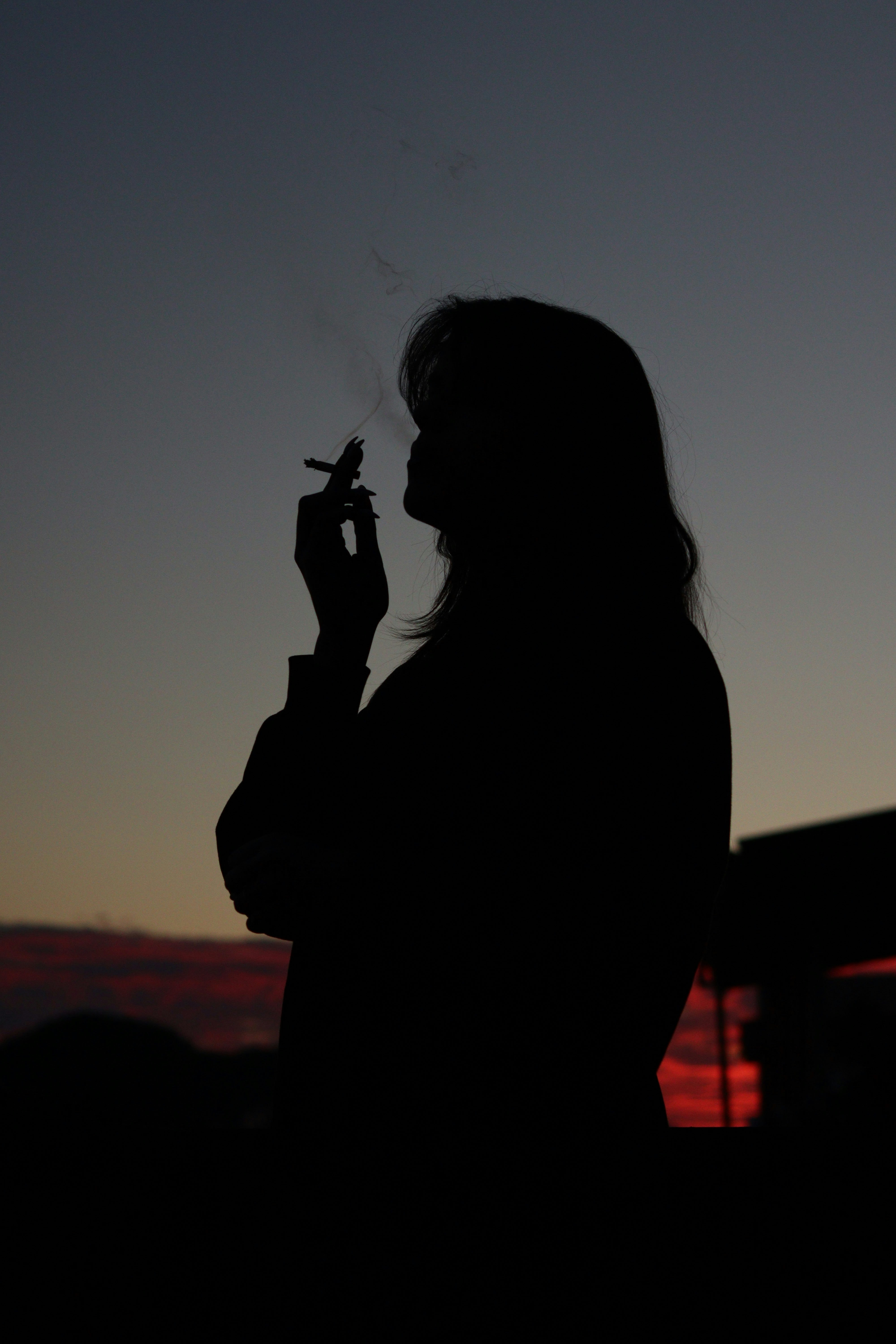 a silhouette of a woman smoking a cigarette