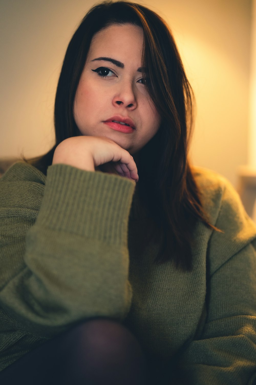 a woman sitting on a couch with her hand on her chin