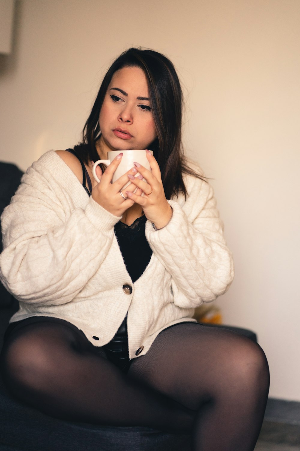 Eine Frau sitzt auf einer Couch und hält eine Tasse Kaffee in der Hand