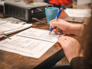 a woman sitting at a table with a pen and paper