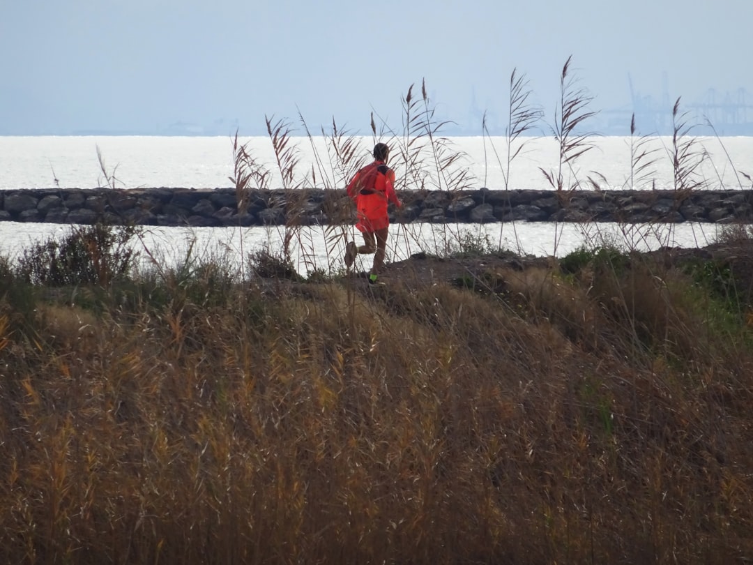 a man in a red shirt is running by the water,