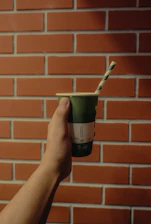 Hands holding biodegradable paper straws over a rustic table setting.