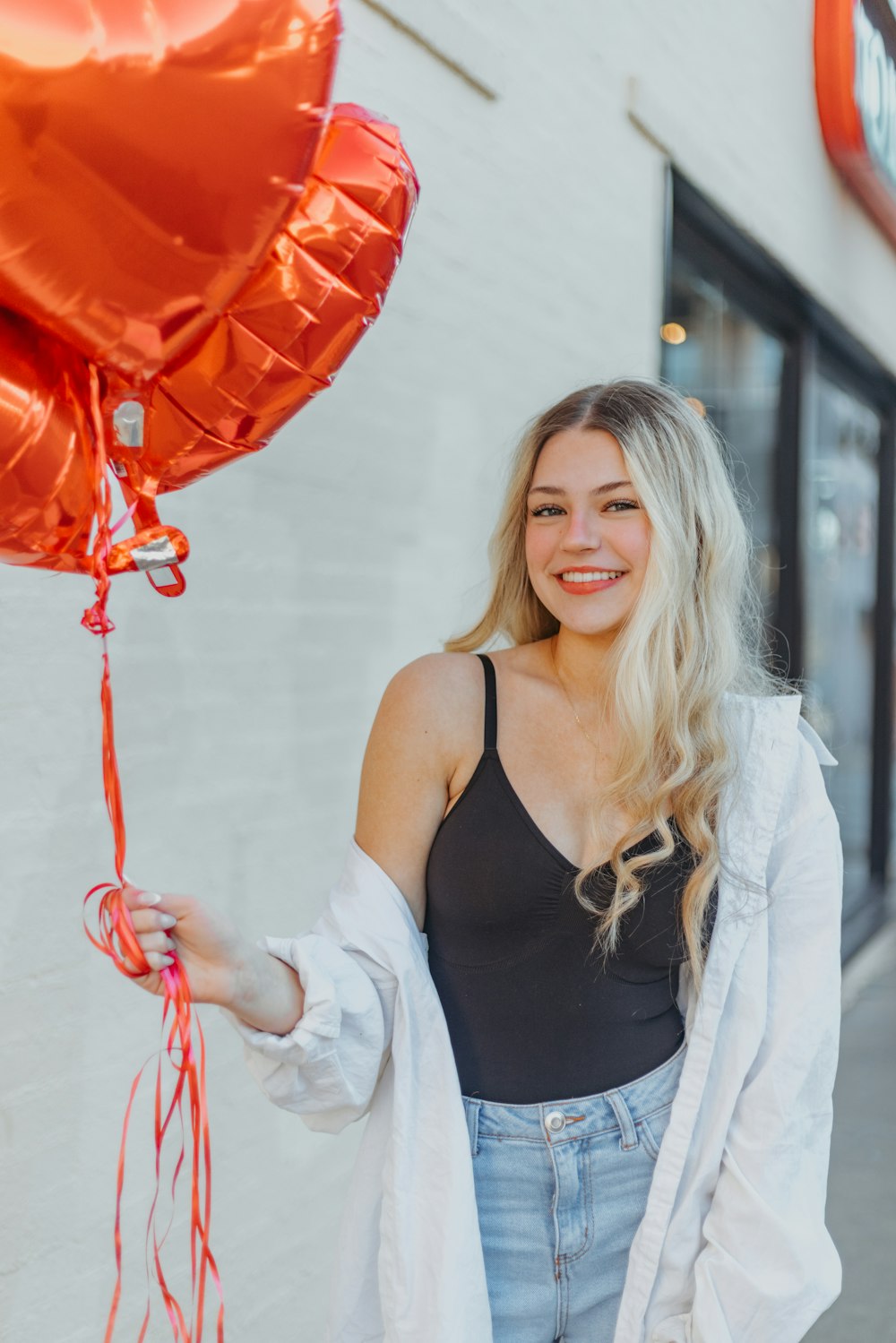 a woman holding a red heart shaped balloon