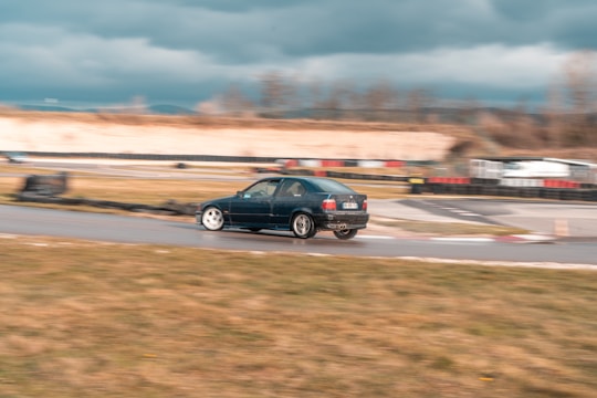 A close-up of a racing car speeding through a twisty track under a cloudy sky.