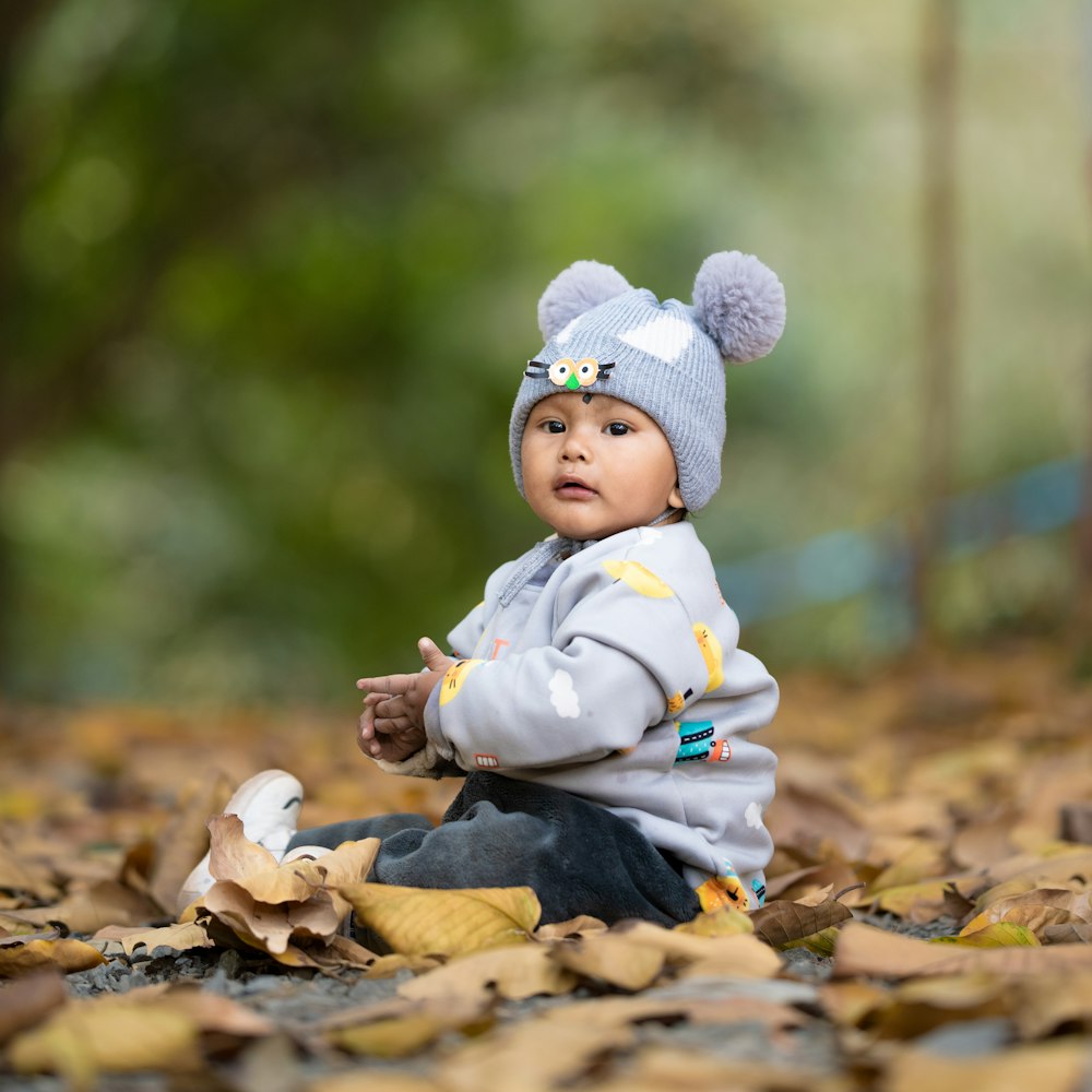 a baby sitting on the ground with a hat on