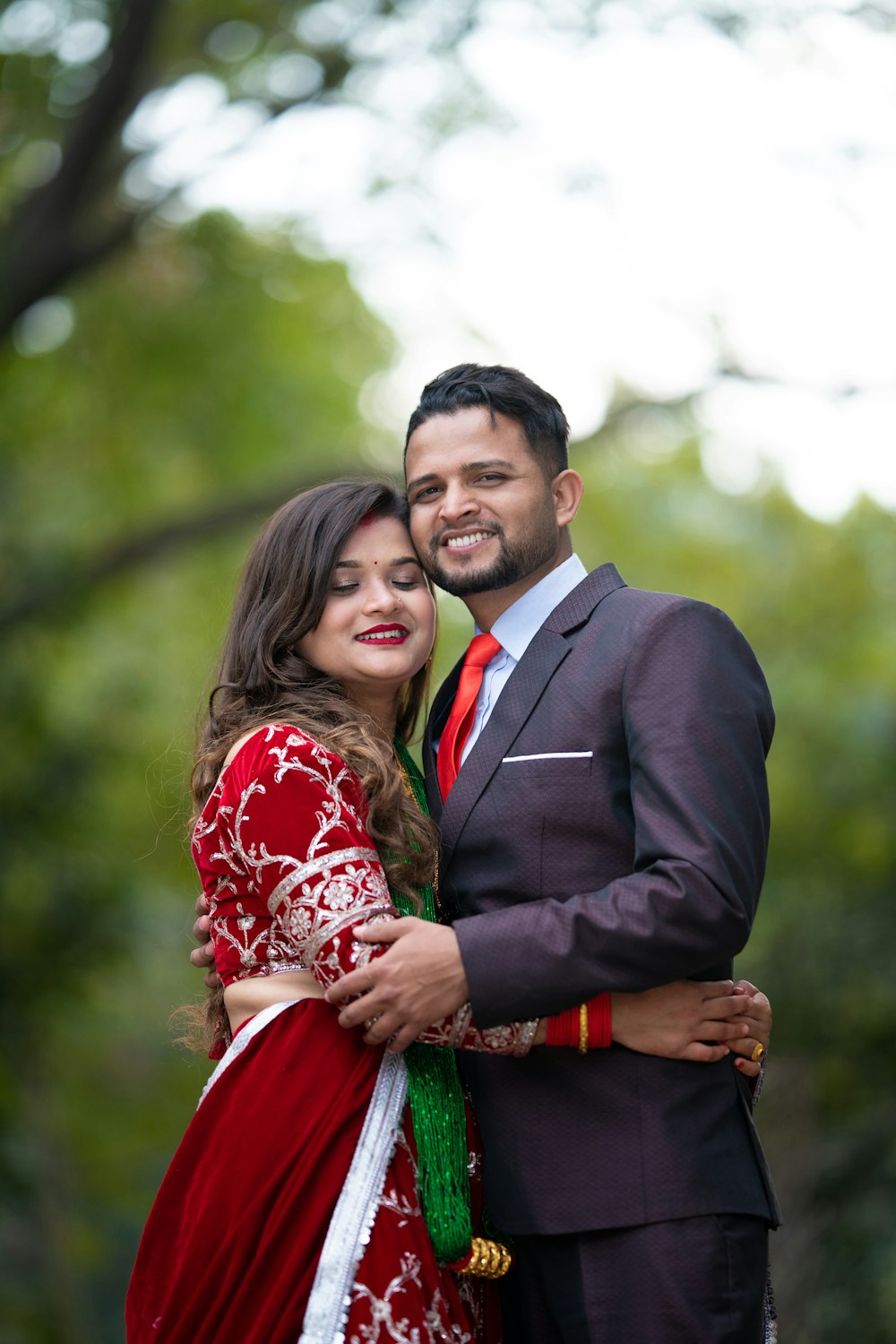 a man in a suit and tie hugging a woman in a red dress