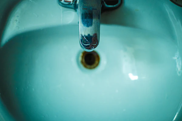 A chrome mixer tap dripping into a pale ceramic basin.
