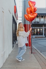 a woman holding a bunch of red balloons