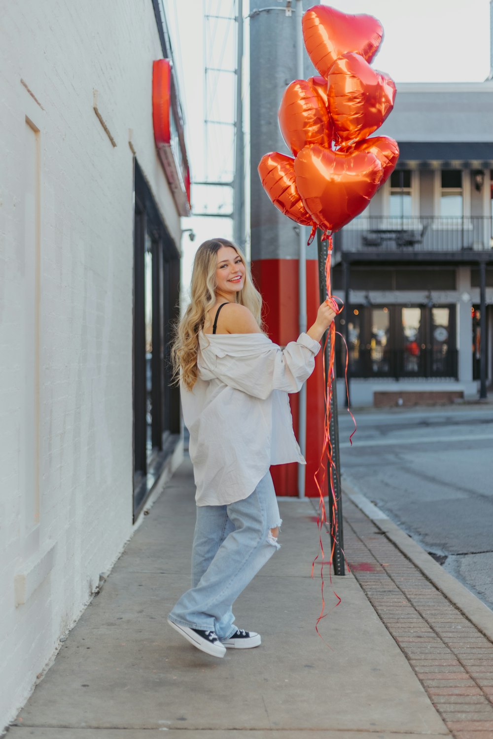 a woman holding a bunch of red balloons