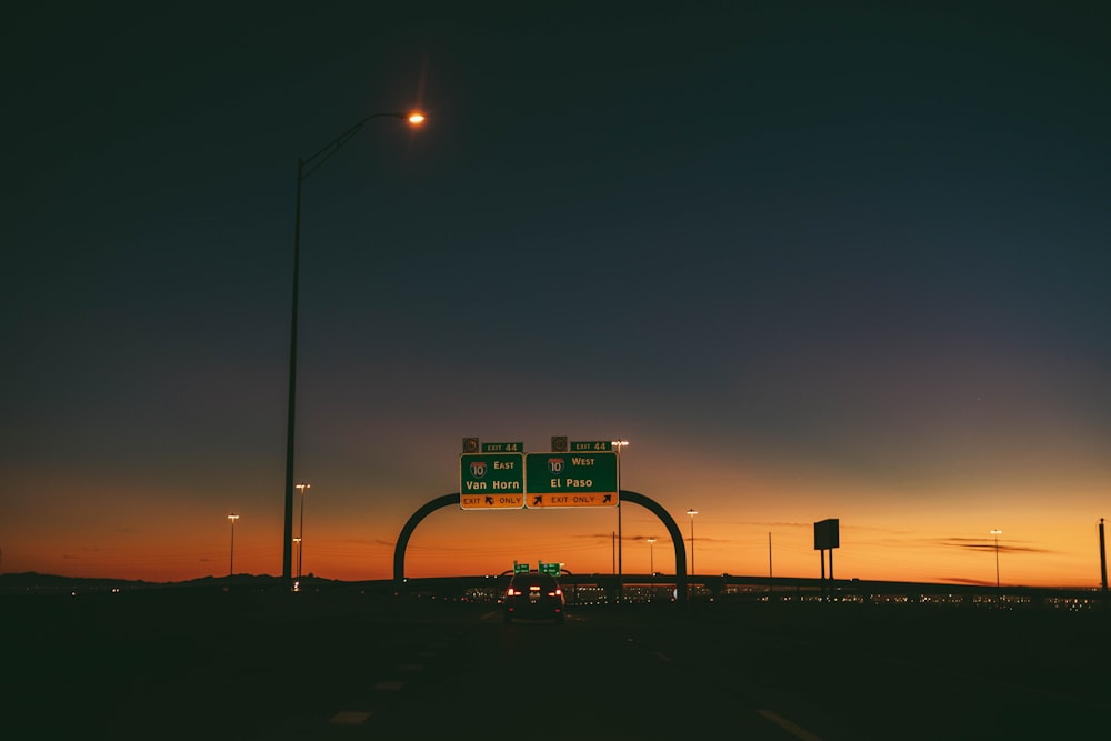 Ein Autobahnschild in der Abenddämmerung mit dem Sonnenuntergang im Hintergrund