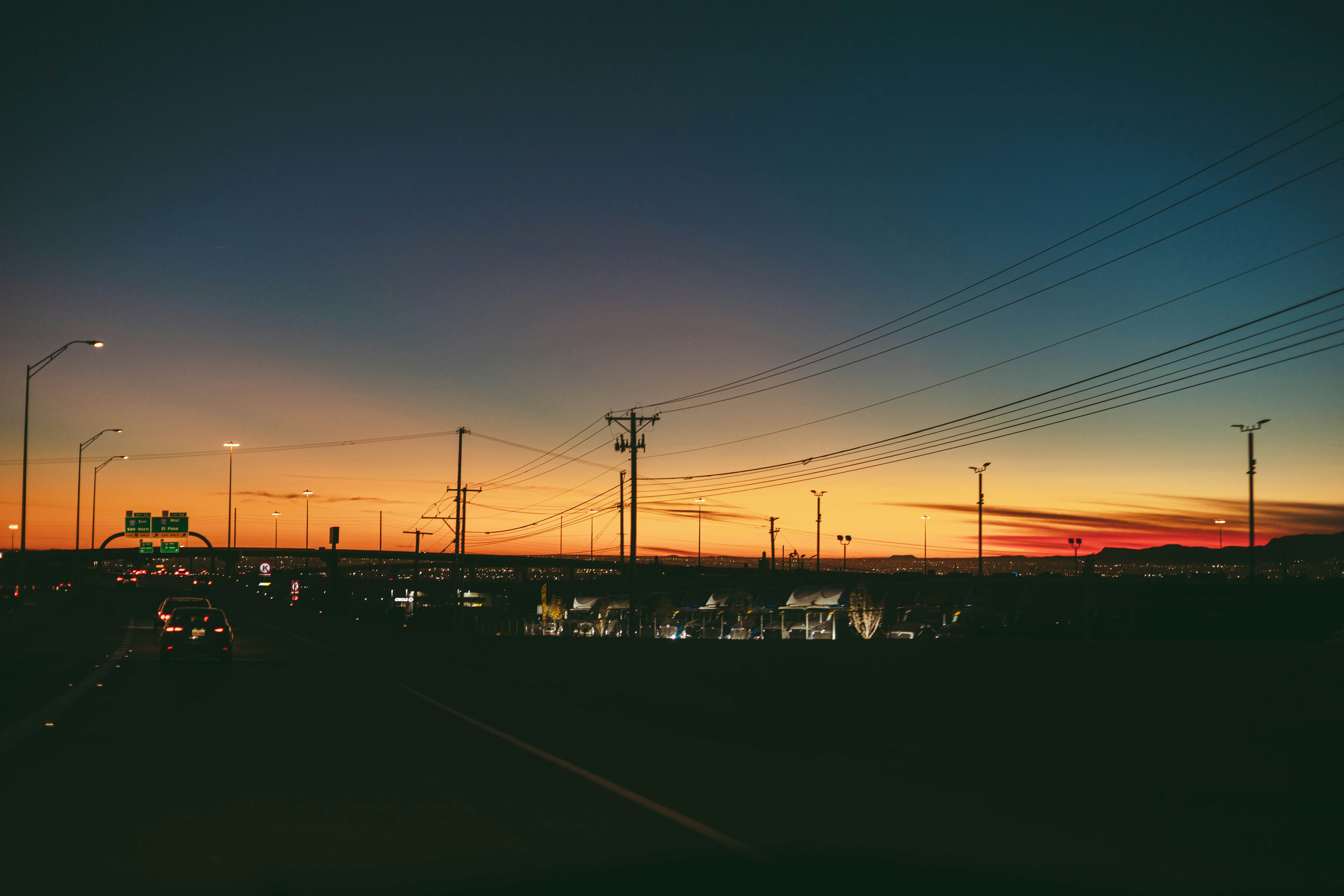 the sun is setting over a city with power lines