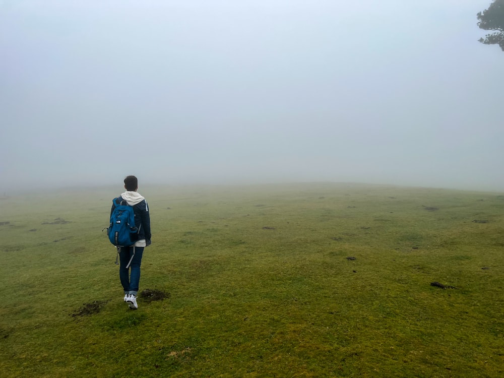 a person standing in a foggy field with a backpack