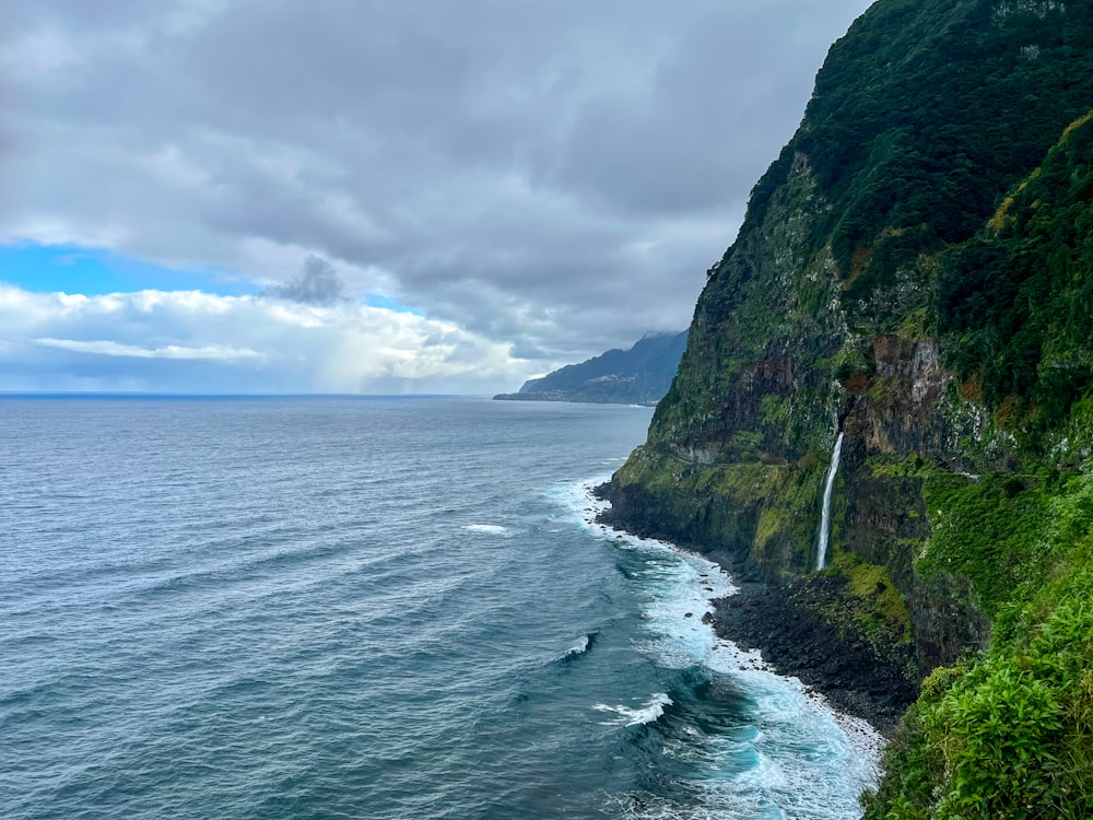 a cliff with a waterfall in the middle of the ocean