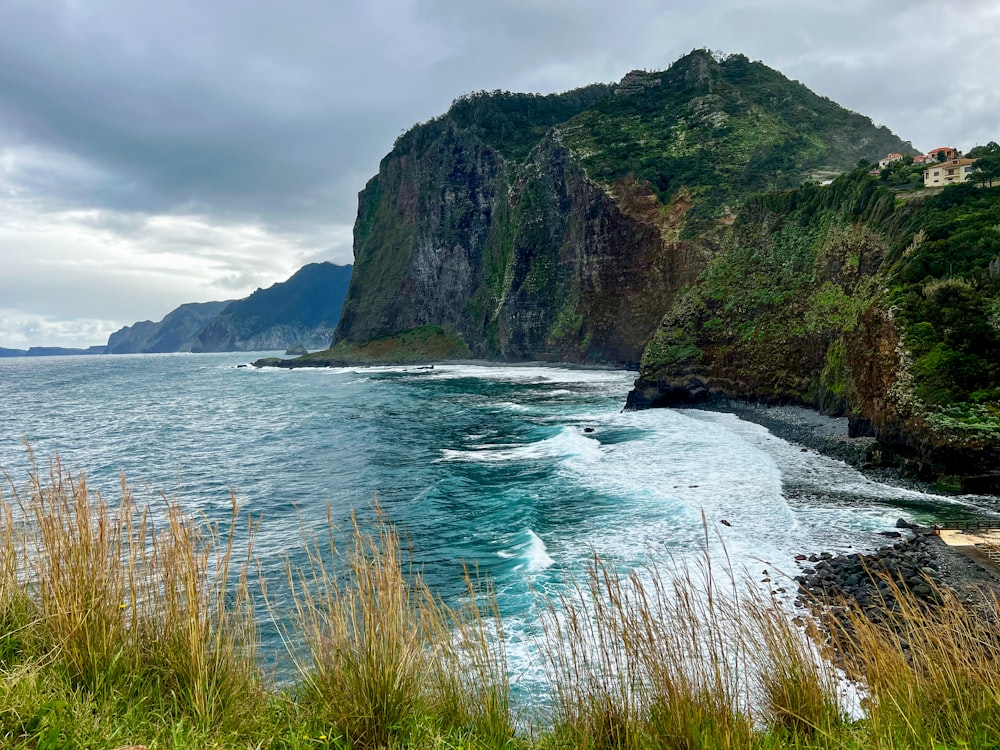 a large body of water next to a lush green hillside