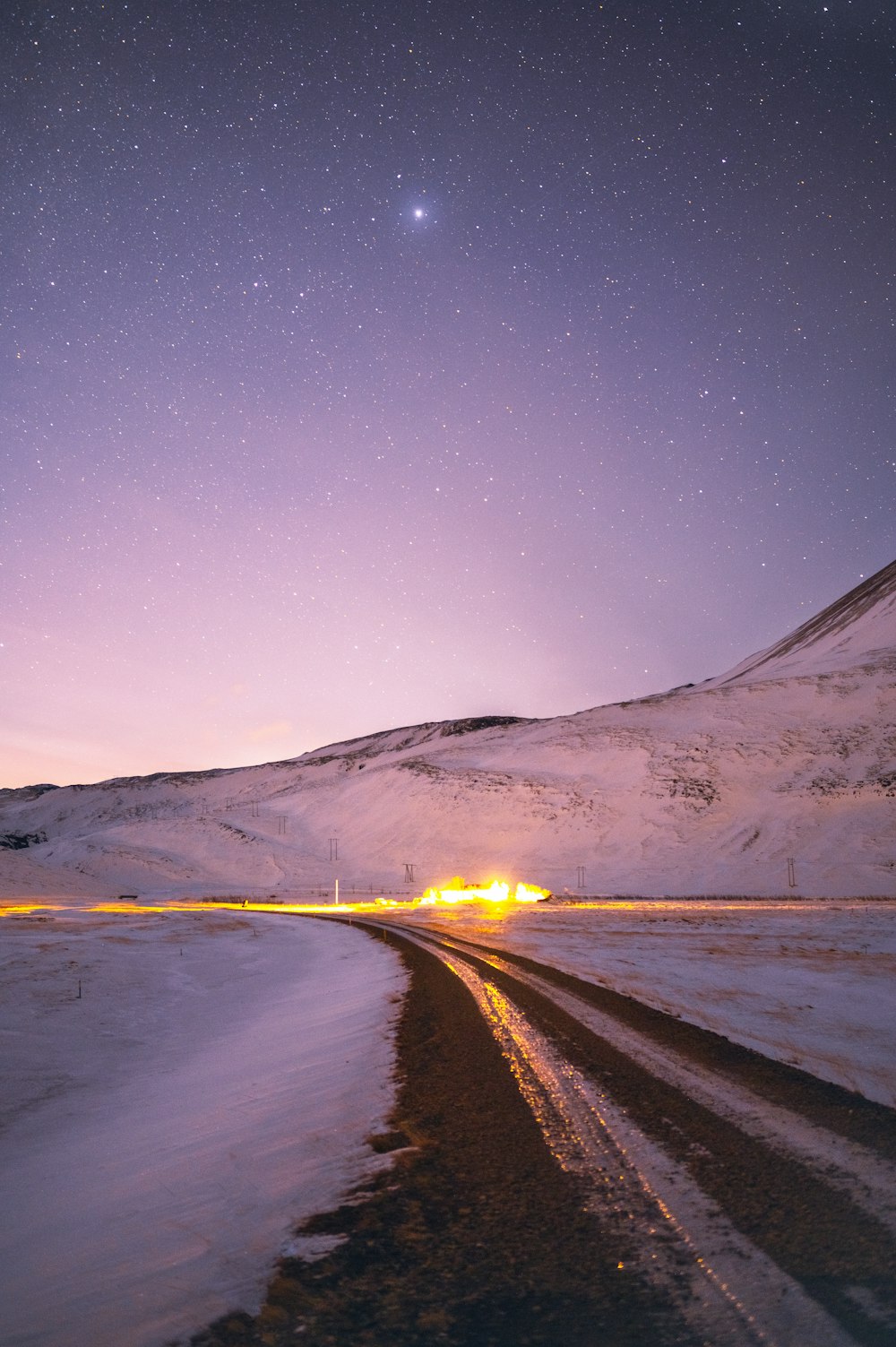 a snowy road with a mountain in the background