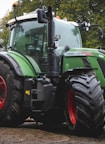 a green tractor parked next to a red tractor