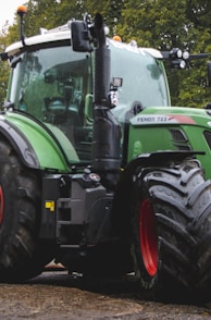 a green tractor parked next to a red tractor