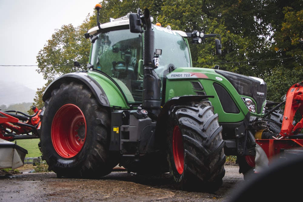 a green tractor parked next to a red tractor