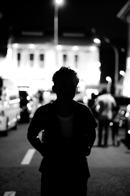 Urban night scene with a figure in black streetwear blending into the shadows.