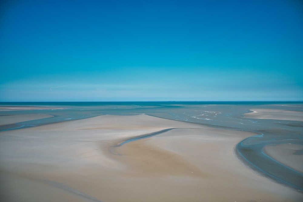 a wide expanse of sand with a blue sky in the background