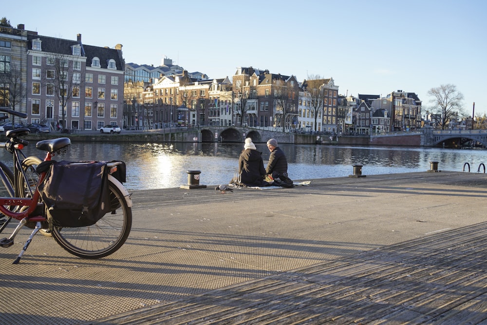 a couple of people sitting on a dock next to a bike