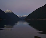 A serene mountain lake reflecting rugged peaks and a pastel sunset.