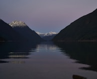 A serene mountain lake reflecting the surrounding peaks at sunset.