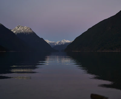 A serene mountain lake reflecting rugged peaks and a pastel sunset.