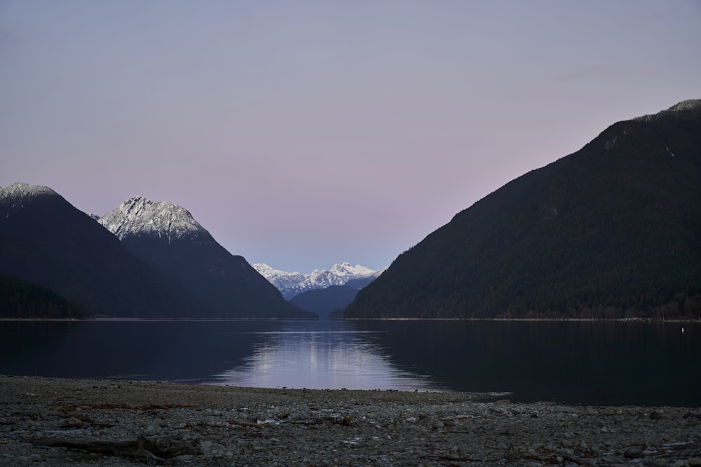 a lake surrounded by mountains with snow on the tops