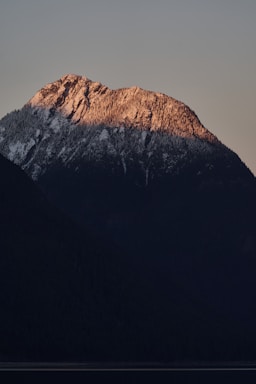 A serene mountain landscape at sunset with warm golden light illuminating the peaks.