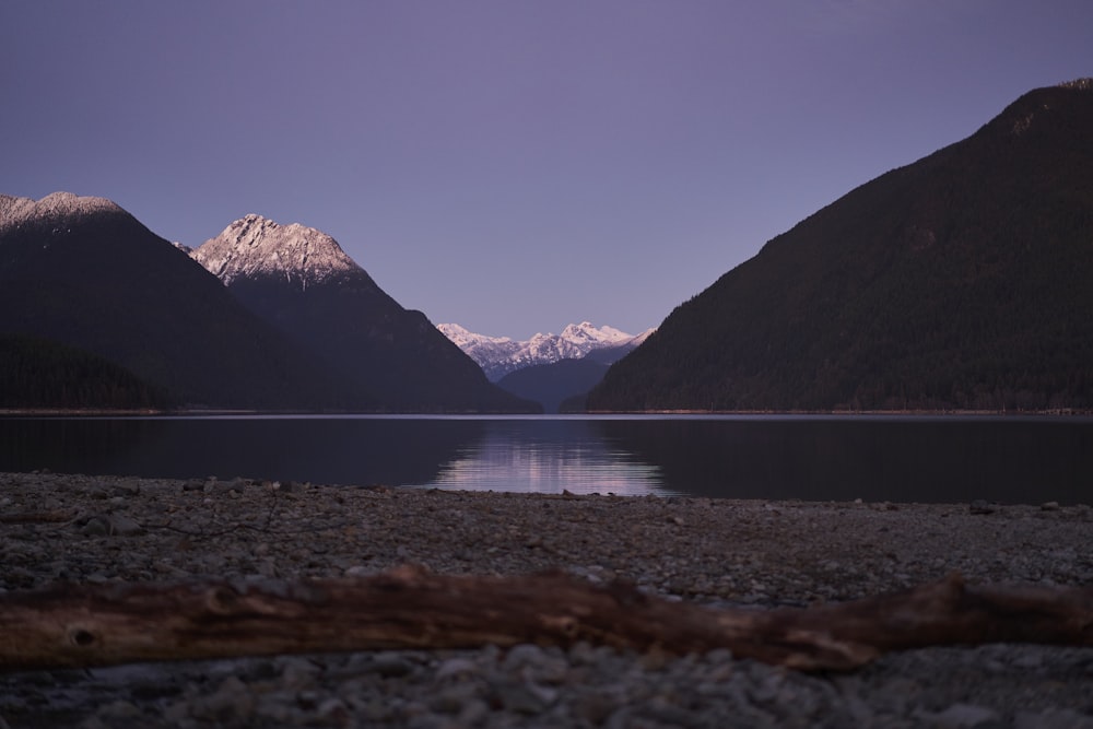 a body of water surrounded by mountains under a blue sky