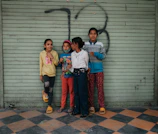 Group shot of three kids in inkweare tees, surrounded by black doodle illustrations on a modern concrete background.