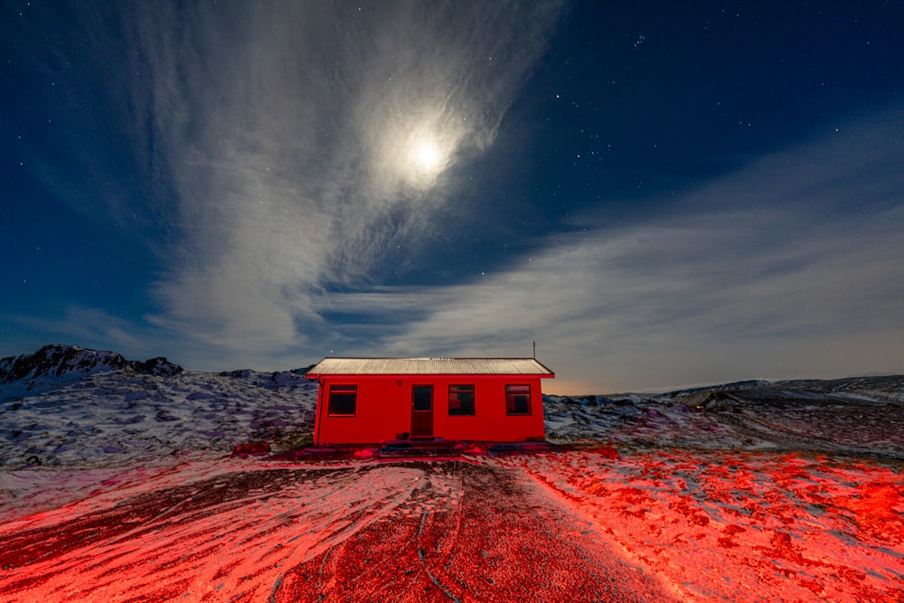a small red building sitting on top of a snow covered field