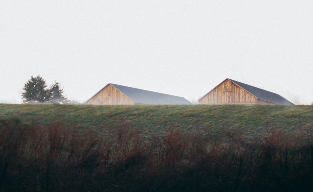 a couple of wooden buildings sitting on top of a lush green field