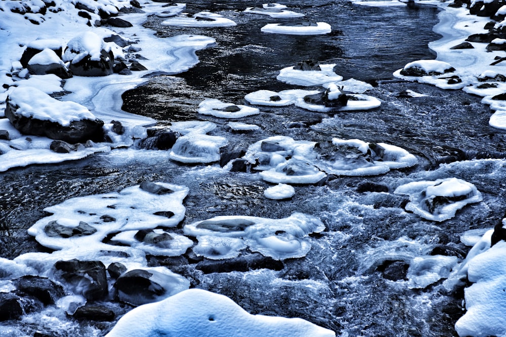 a river with snow covered rocks and water
