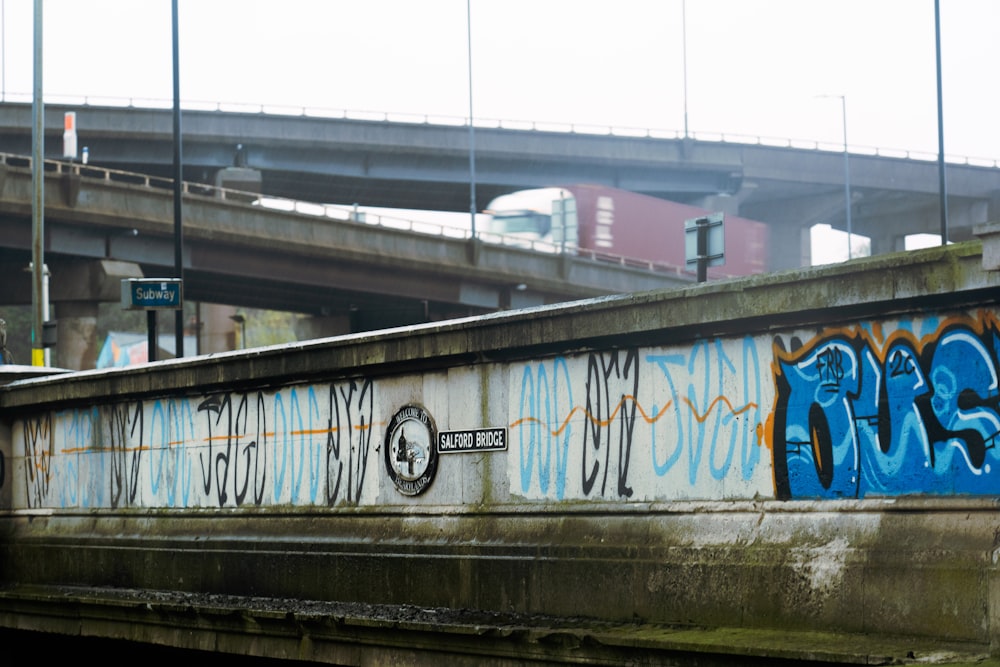 a bridge with graffiti on it next to a highway